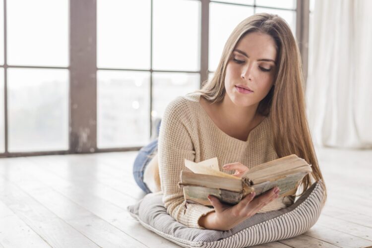 vrouw ligt op de grond een boek te lezen