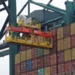 Containerkraan verplaatst zeecontainers in haven, cruciaal voor klantbeleving in logistiek.