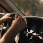 Handen houden stuur vast tijdens autorit met dashboard op de achtergrond