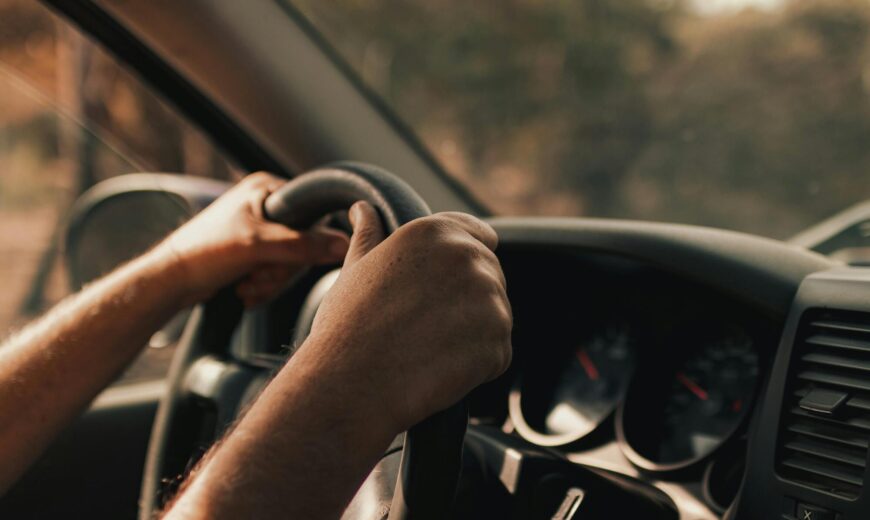 Handen houden stuur vast tijdens autorit met dashboard op de achtergrond