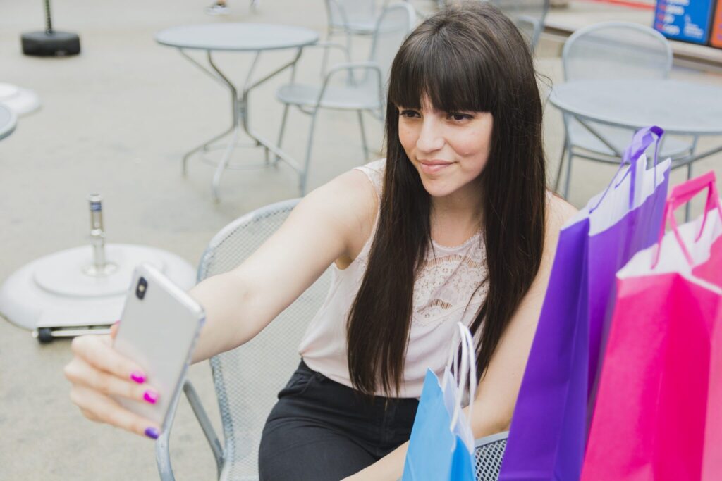 vrouw neemt een selfie met shopping bags